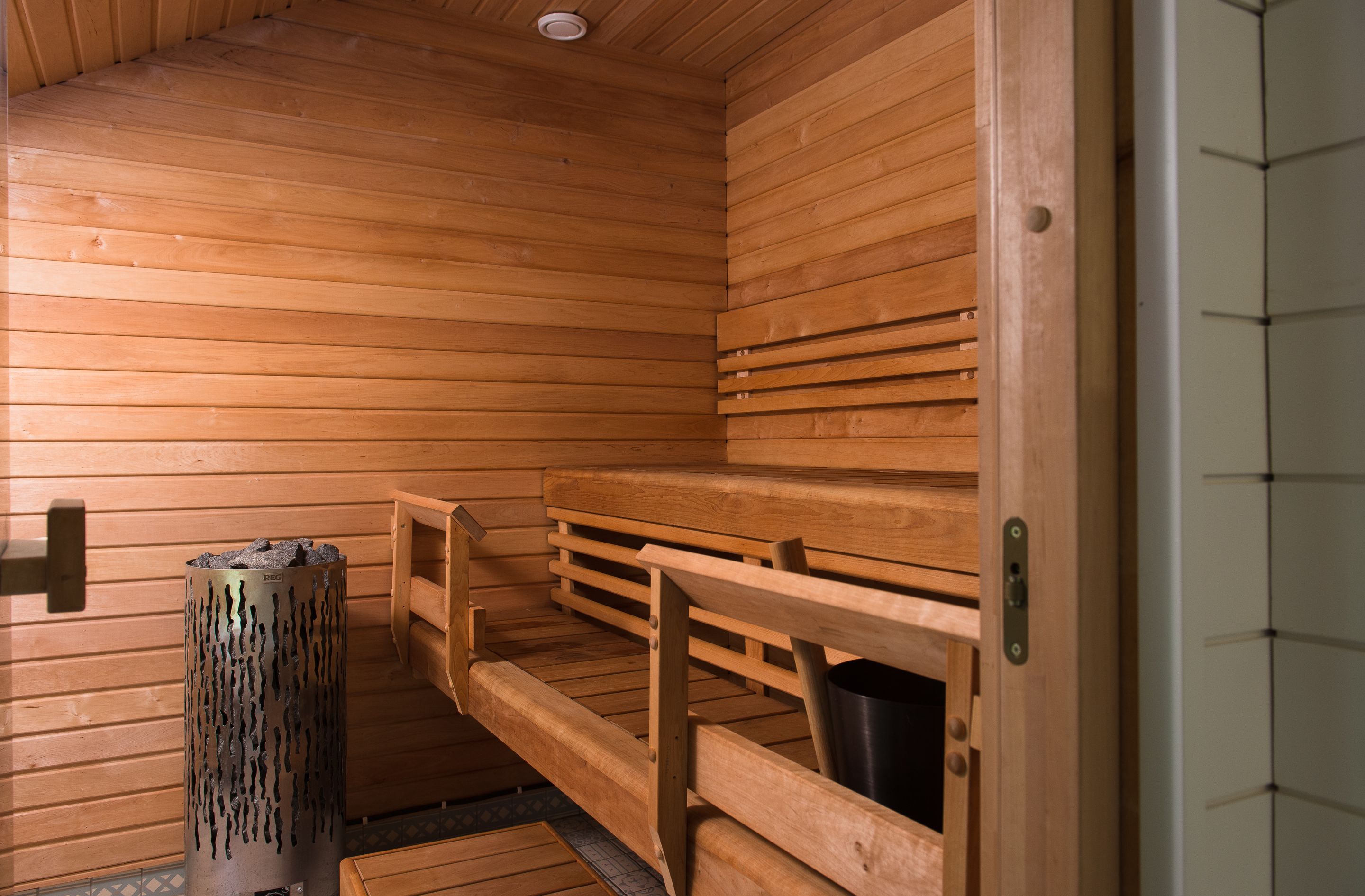 A sauna with wooden benches and a central heating column.