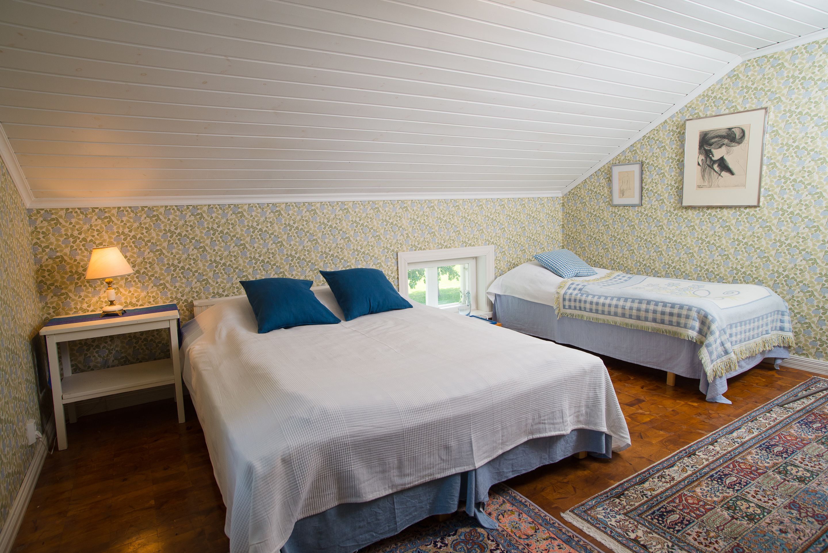 Una camera da letto con due letti, un comodino, una lampada e un tappeto decorato.
