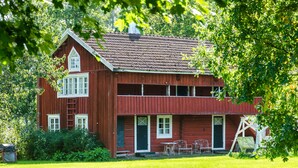 A red wooden house with a front porch, a chimney, and a ladder leading to the attic. - Koivulan Kartano (Lohja)