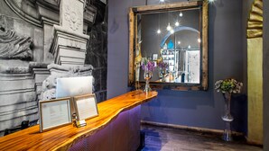 Un comptoir d’accueil orné de cadres contenant des certificats, un miroir et un vase de fleurs.