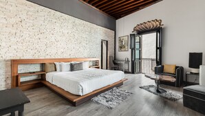 Une chambre à coucher moderne avec un mur en briques, un cadre de lit en bois, un bureau et un coin salon.