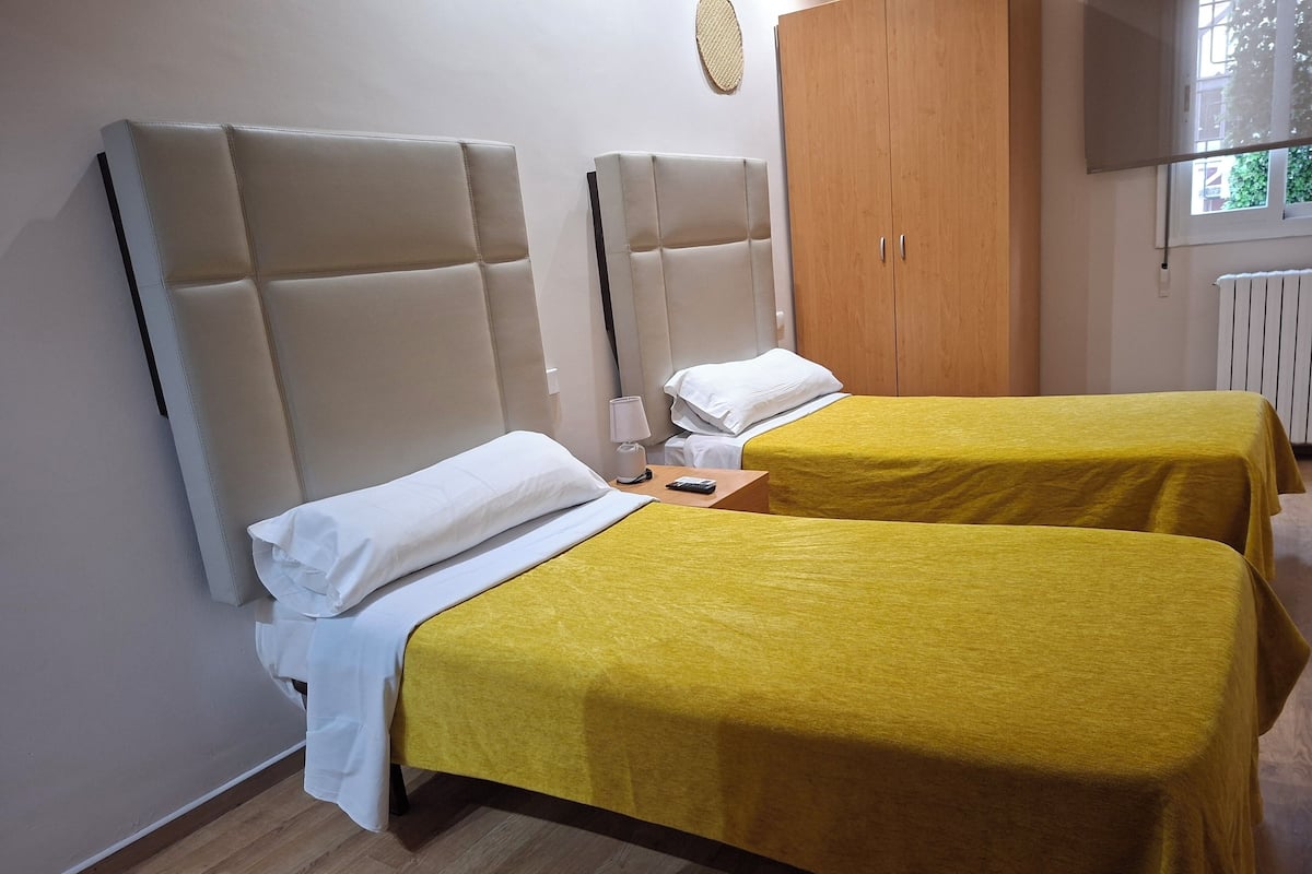 A hotel room with two beds, a wooden wardrobe, and a television.