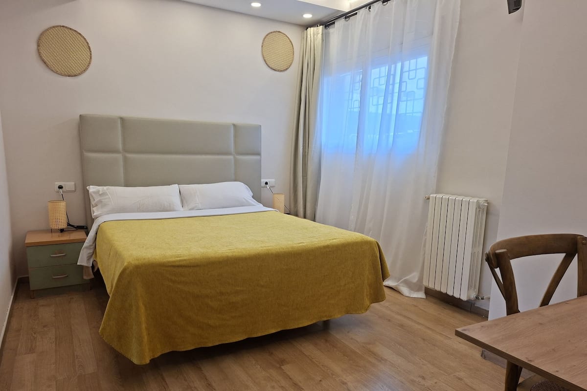 A bedroom with a bed, a nightstand, a table, and a chair.