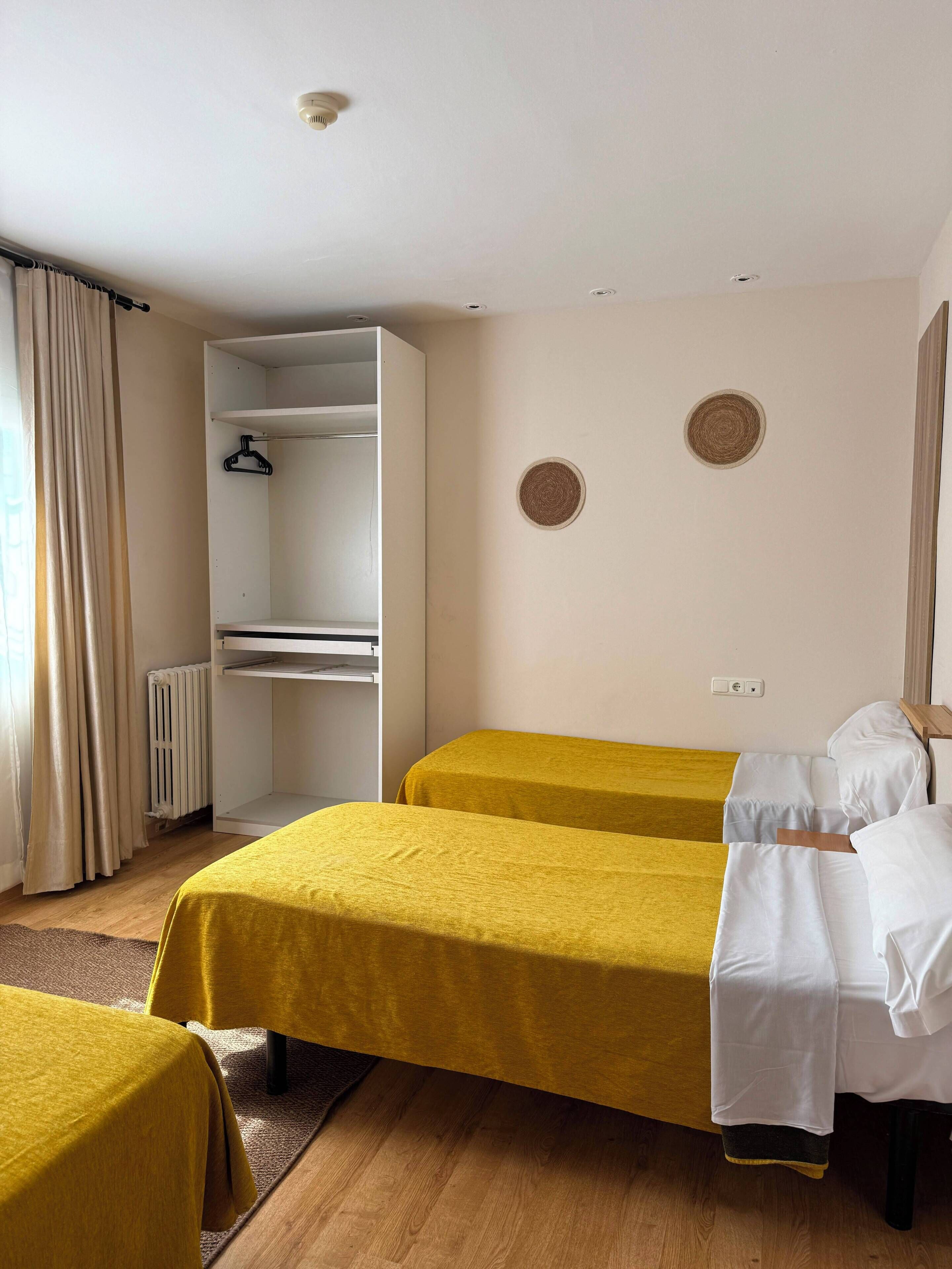 A room with two beds, a wardrobe, and a radiator.