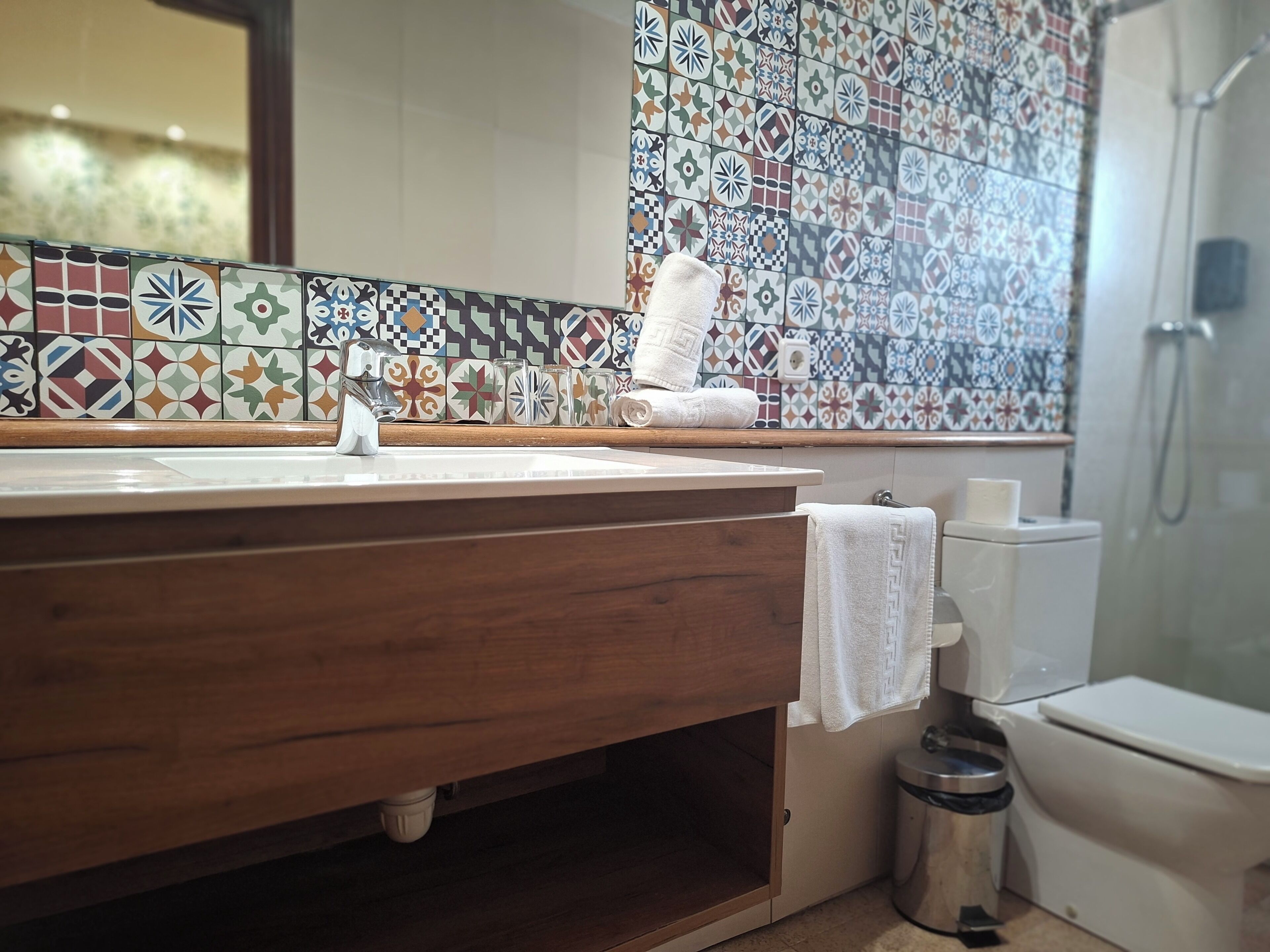 Une salle de bain avec un meuble-lavabo en bois, un pare-feu en carrelage, des toilettes et un espace douche.