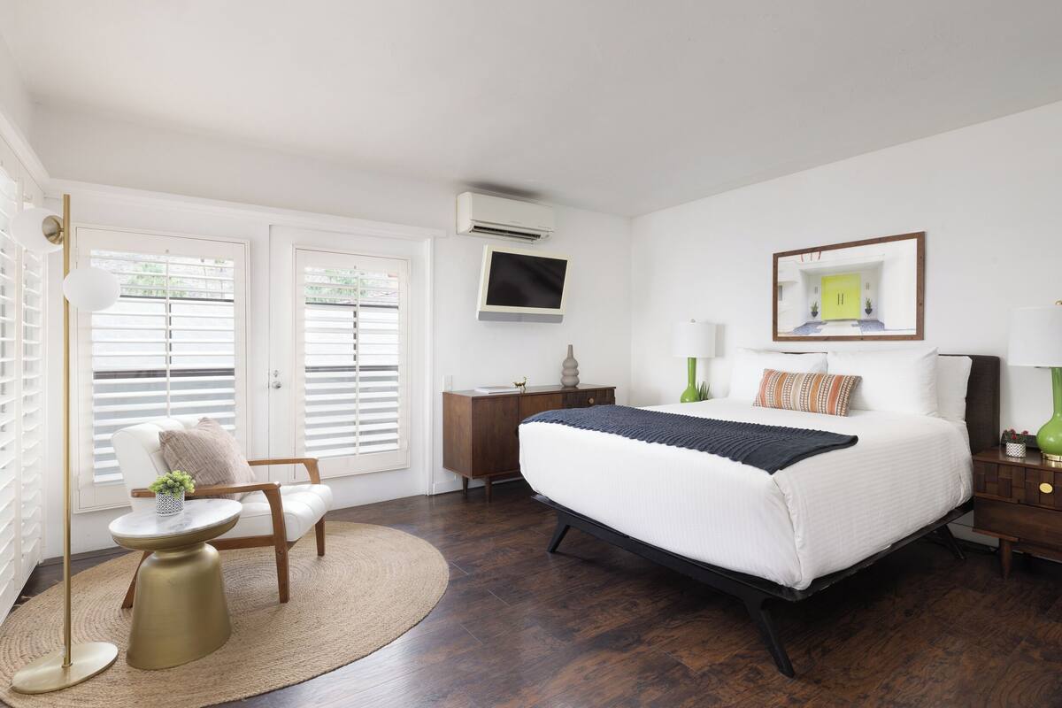 A bedroom with a large bed, a desk, a chair, and a TV.