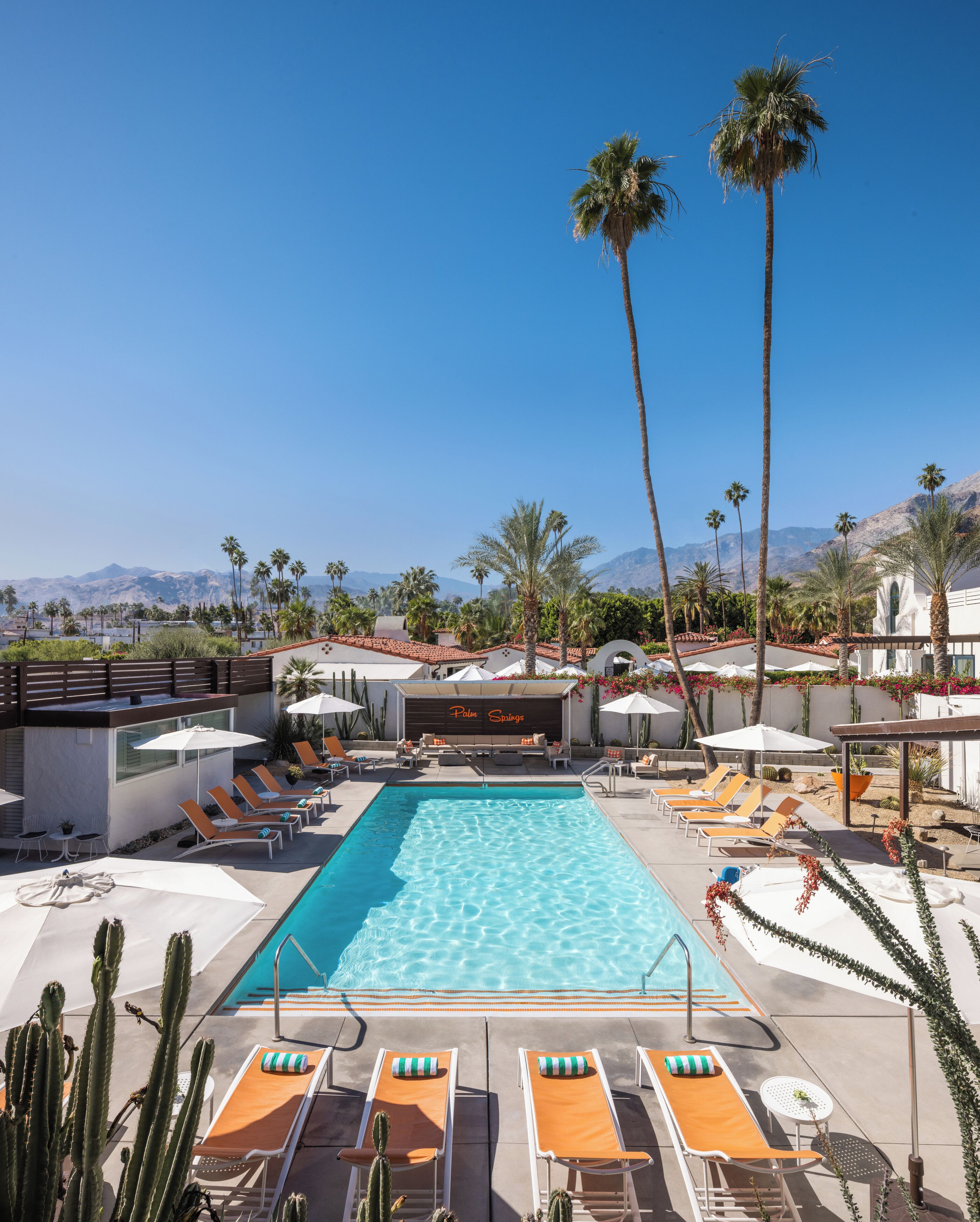 A pool area with lounge chairs, palm trees, and a mountain backdrop.