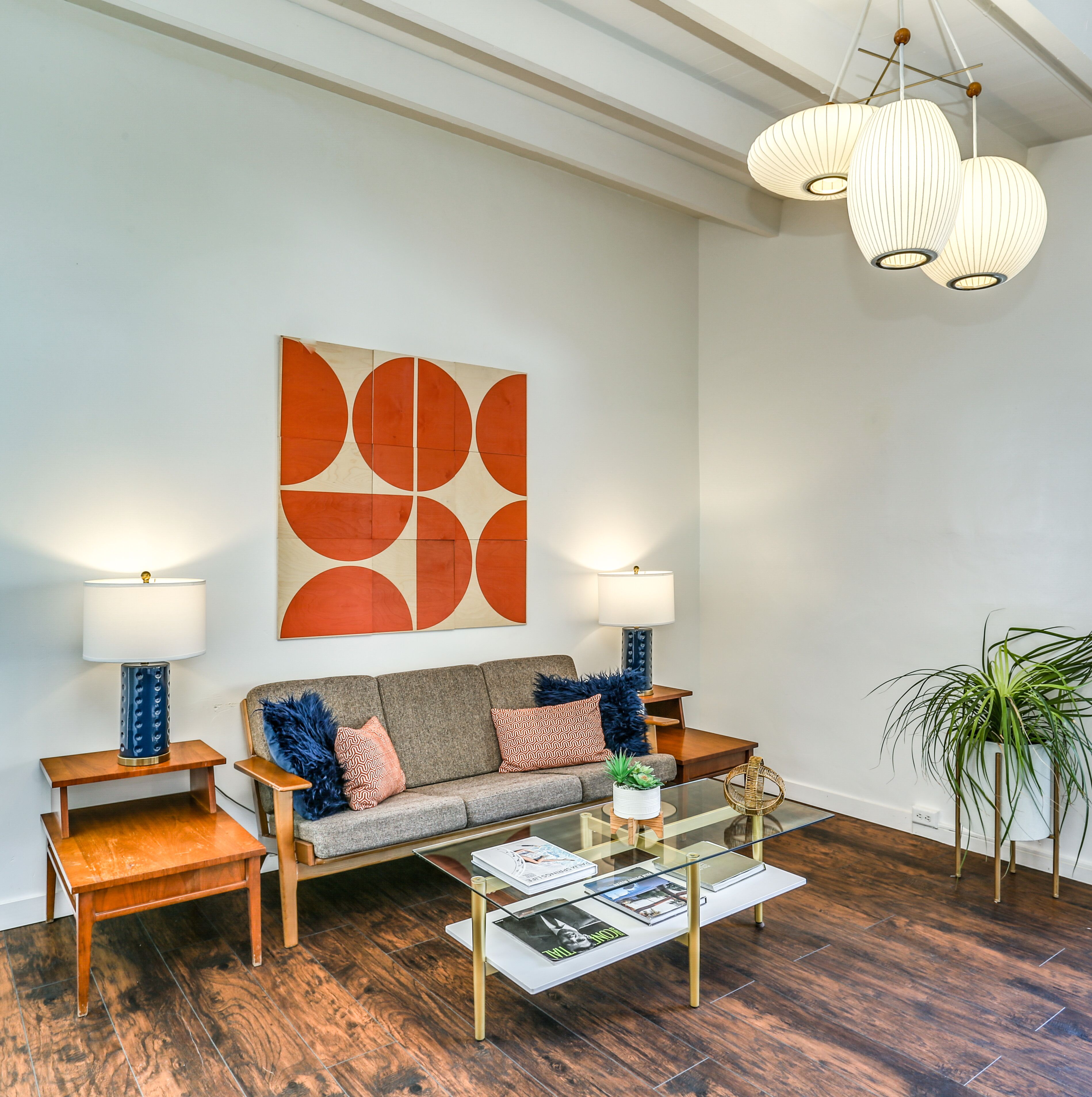 A living room with a sofa, two side tables, a coffee table, and a large abstract painting on the wall.