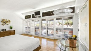 Una camera da letto con un letto, un tavolino in vetro con un secchio, una TV e vista all'esterno.