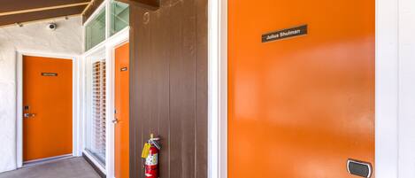 Un pasillo con puertas naranja, un extintor y una placa identificadora en una puerta.