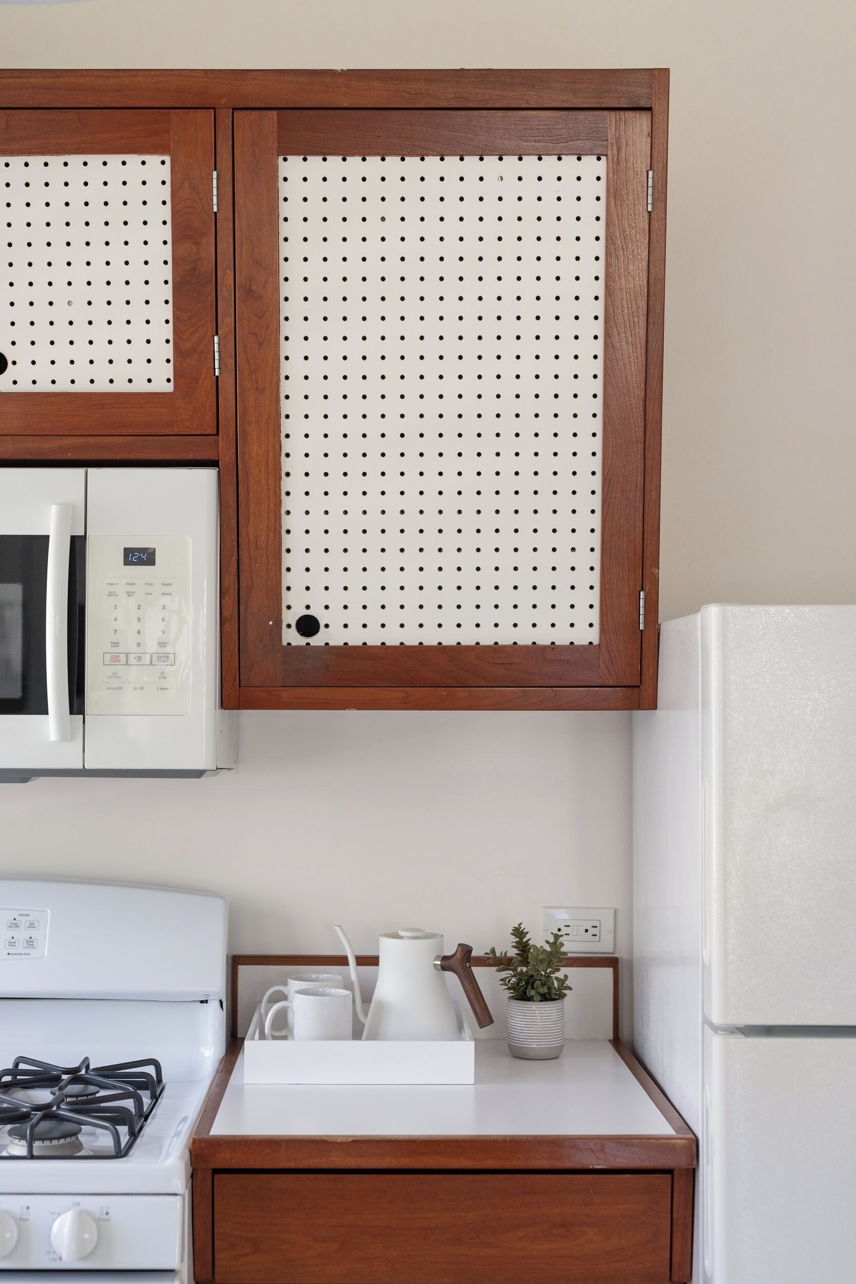 Une cuisine avec des meubles de rangement en bois, une cuisinière blanche, un four à micro-ondes et un réfrigérateur.