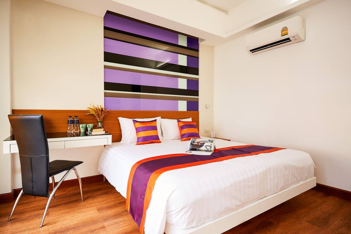 A hotel room with a bed, a desk, and a chair.