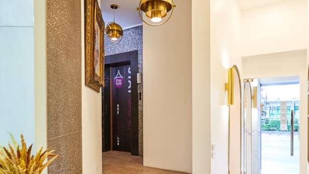 A hotel lobby with a marble staircase, a reception desk, and a framed picture on the wall. - Studio Asoke (Bangkok)