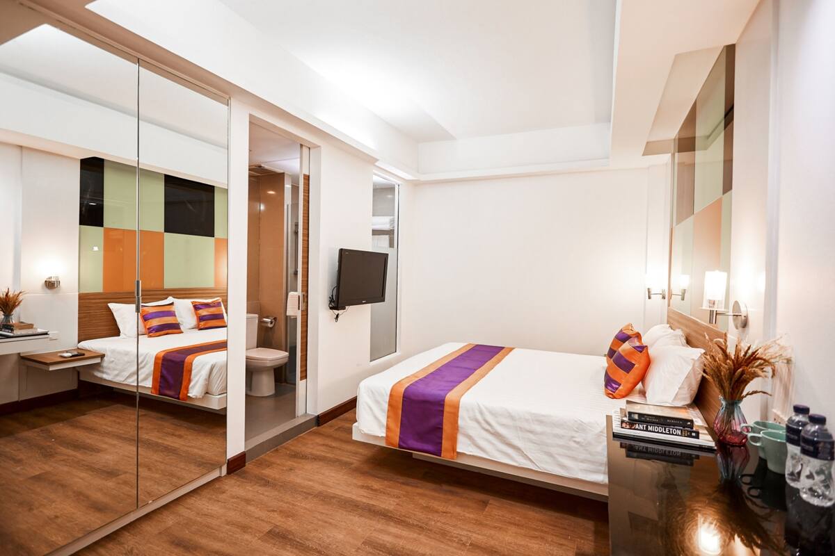 A modern hotel room with a bed, bedside table, and a mirror.