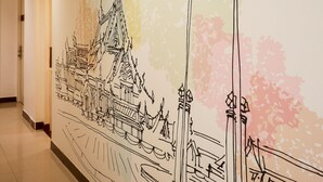 A hallway with a wall mural depicting traditional Thai architecture, including a temple and a bridge. - Studio Asoke (Bangkok)
