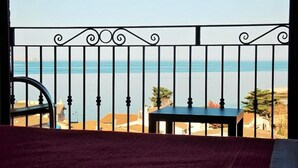 Un balcón con barandilla de metal, una mesita pequeña y vista al mar.