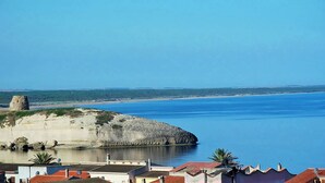 Vista costera con un destacado afloramiento rocoso y un mar azul cristalino.
