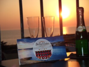 Une brochure de l’hôtel Bella Vista présentant une vue au coucher du soleil, deux verres et une bouteille.