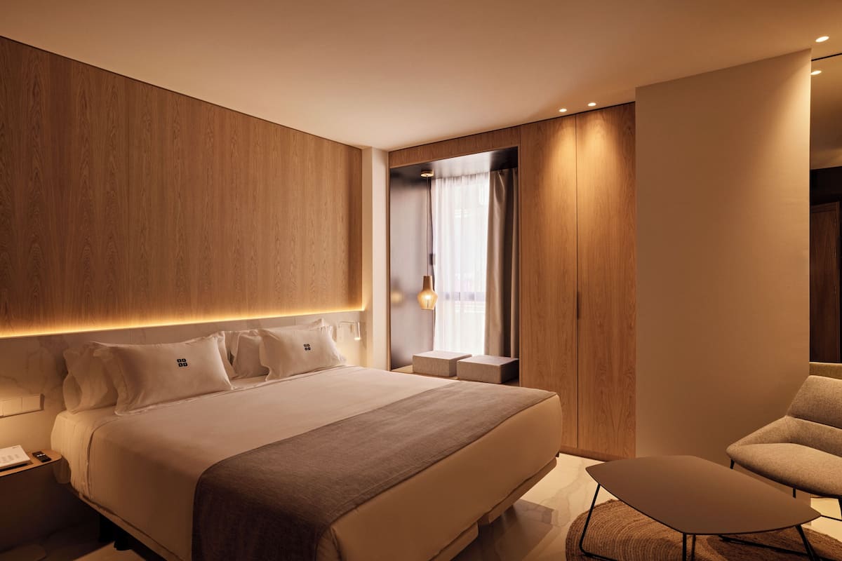Une chambre d’hôtel moderne avec un grand lit, une petite table et une chaise.