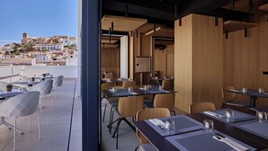Un comedor moderno con mesas y sillas, vistas a un paisaje urbano y un interior de madera.
