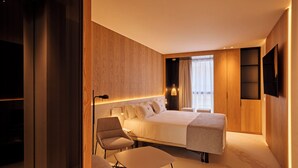 Una habitación de hotel moderna con una cama grande, un espacio para sentarse y un televisor montado en la pared.