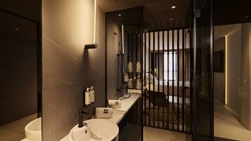 Un baño moderno con dos lavamanos, zona de ducha y mampara de vidrio.
