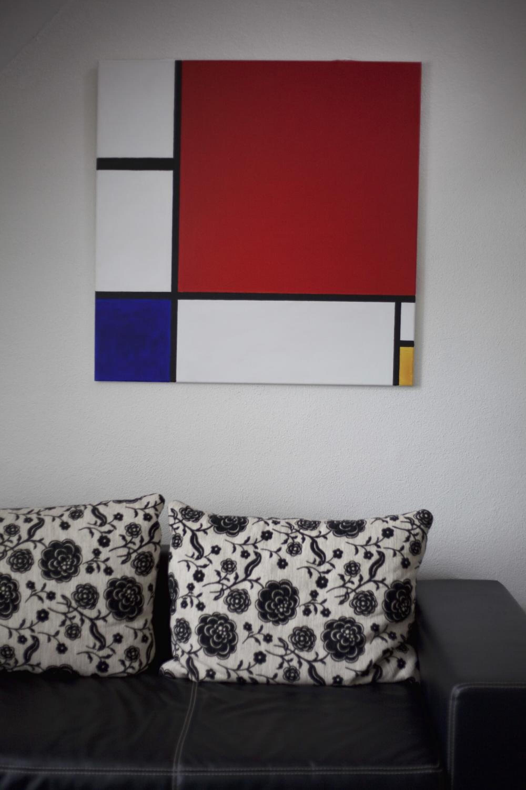 Ein modernes Wohnzimmer mit einem schwarzen Ledersofa und Kissen mit Muster.