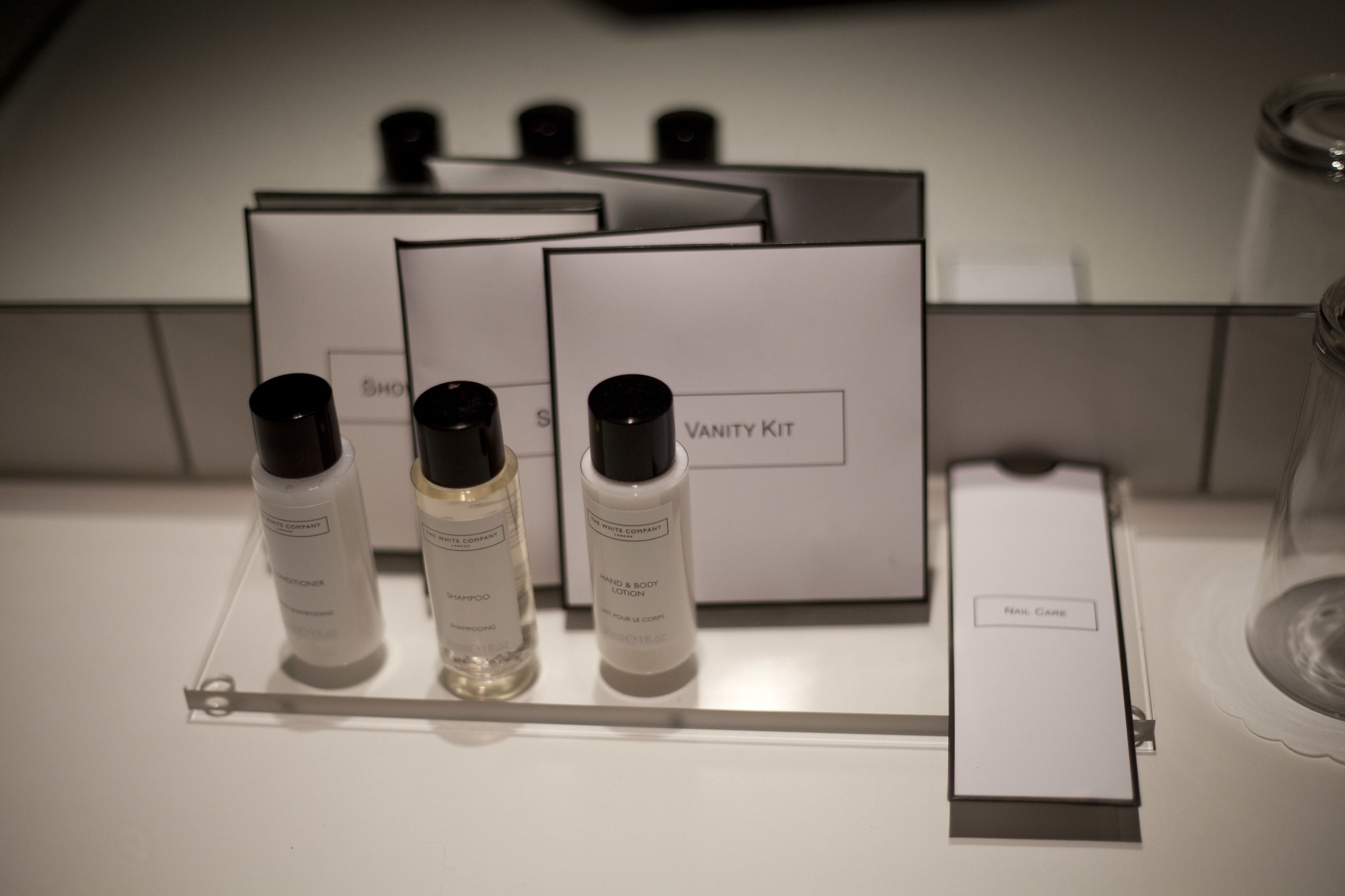 A vanity kit with bottles of shampoo, body lotion, and a nail care item, along with a vanity mirror.