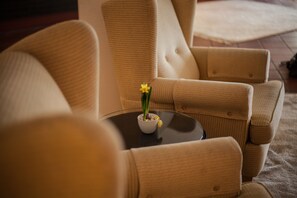 A beige armchair with a small table in front of it, featuring a white bowl with a yellow flower. - Hotel Das Goldene Lamm (Aalen)