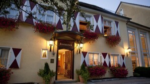 A building with a sign reading "Restaurant" at the entrance, surrounded by potted plants and flowering vines. - Hotel Das Goldene Lamm (Aalen)