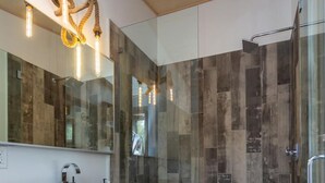 Un baño moderno con tocador de madera, un espejo grande y cabina de ducha de vidrio.