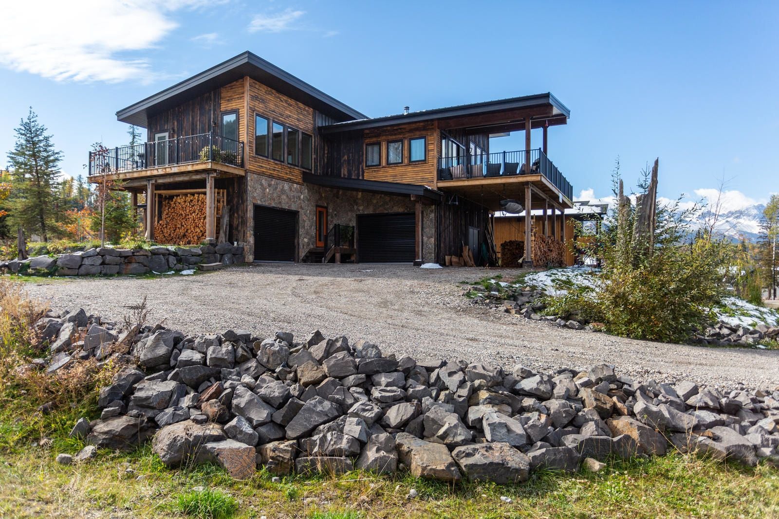 A modern two-story house with a stone facade, large windows, and a covered porch.