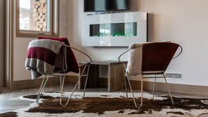 Una sala de estar moderna con dos sillones, un televisor y una mesa de madera.