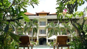 Un resort con un patio central, varios balcones y abundante vegetación.