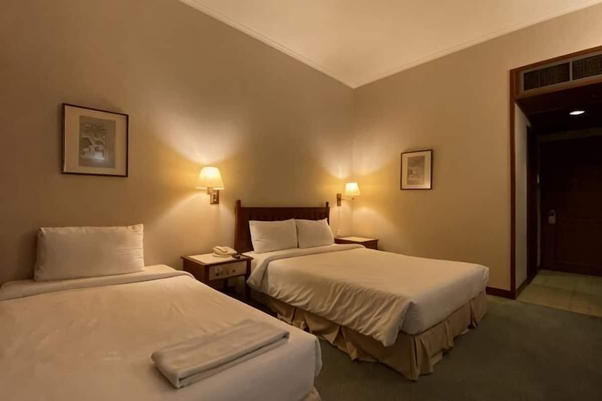 A hotel room with two beds, bedside lamps, a nightstand, and a framed picture on the wall.