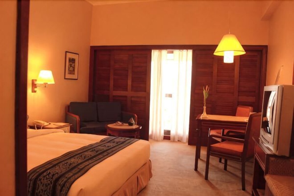 Een hotelkamer met een bed, een bureau, een stoel, een televisie en een lamp.