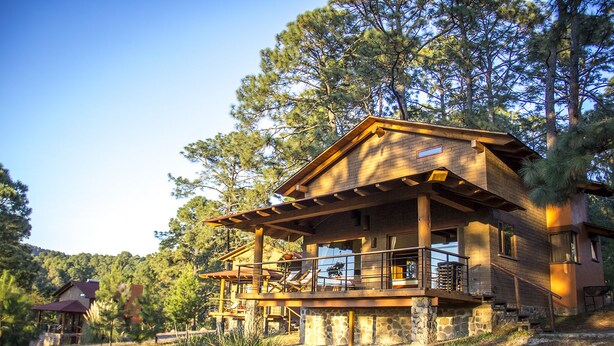 A two-story wooden cabin with a balcony, surrounded by trees. - Cabañas Monterra Tapalpa (Tapalpa)
