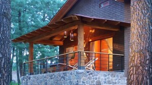 A cabin with a stone foundation, wooden beams, and a balcony with a metal railing. - Cabañas Monterra Tapalpa (Tapalpa)