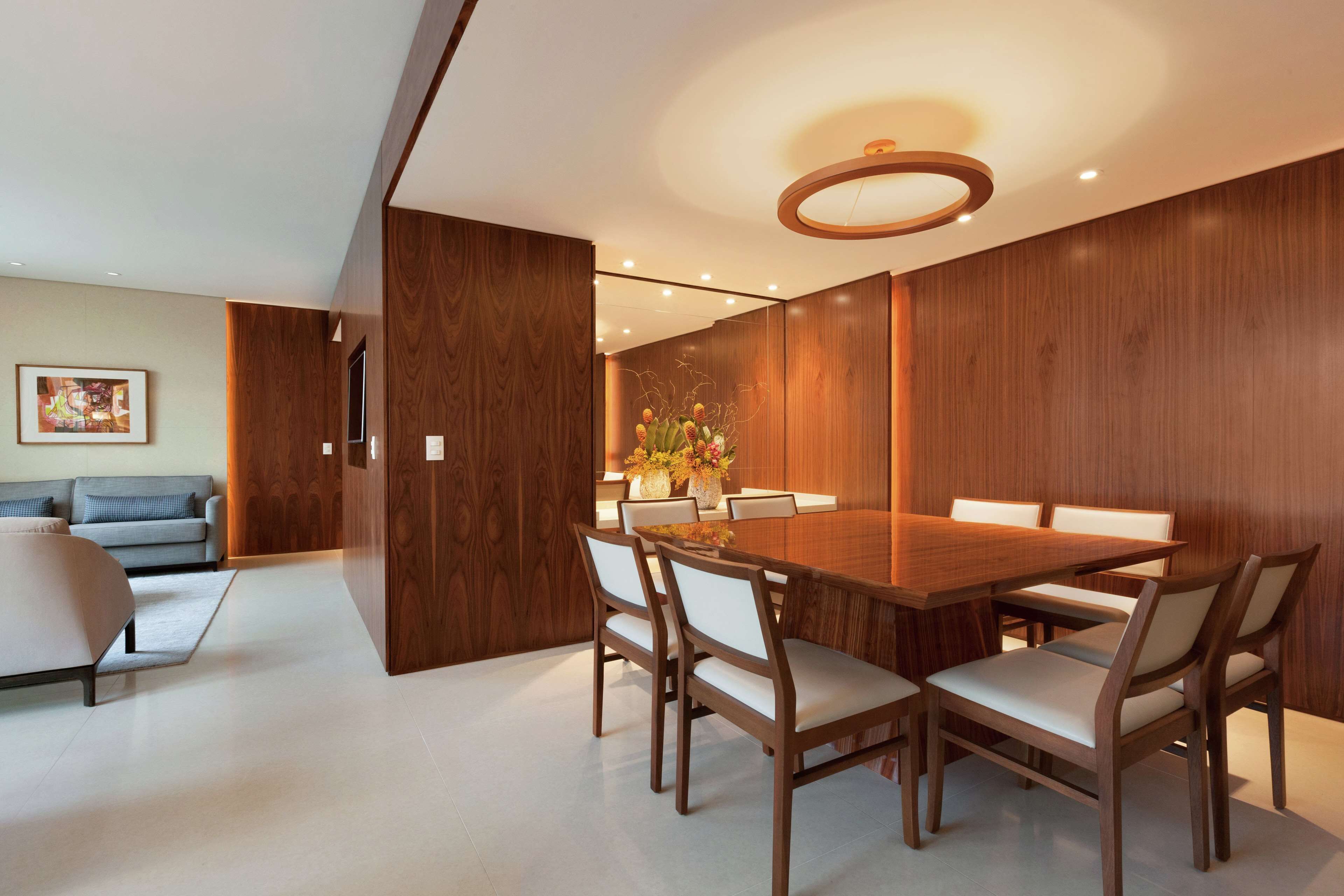 A modern dining area with a wooden table and chairs, a sofa, and a decorative vase.