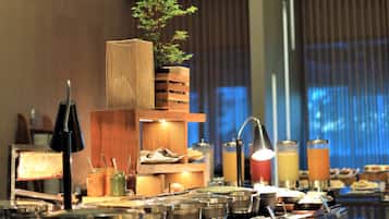 A buffet setup with various food containers, a plant, and a water dispenser.