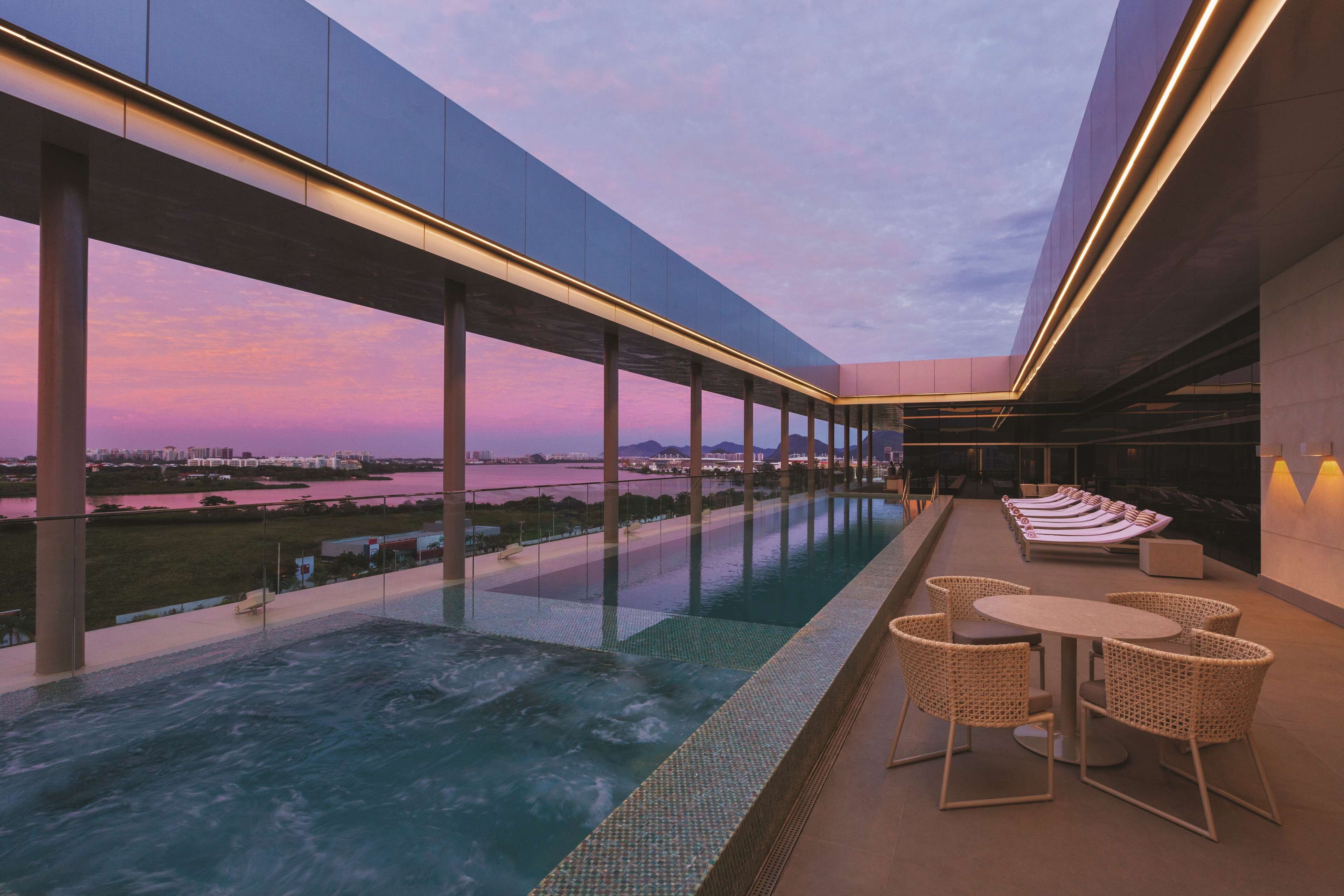 An outdoor infinity pool with a view of a cityscape at dusk.