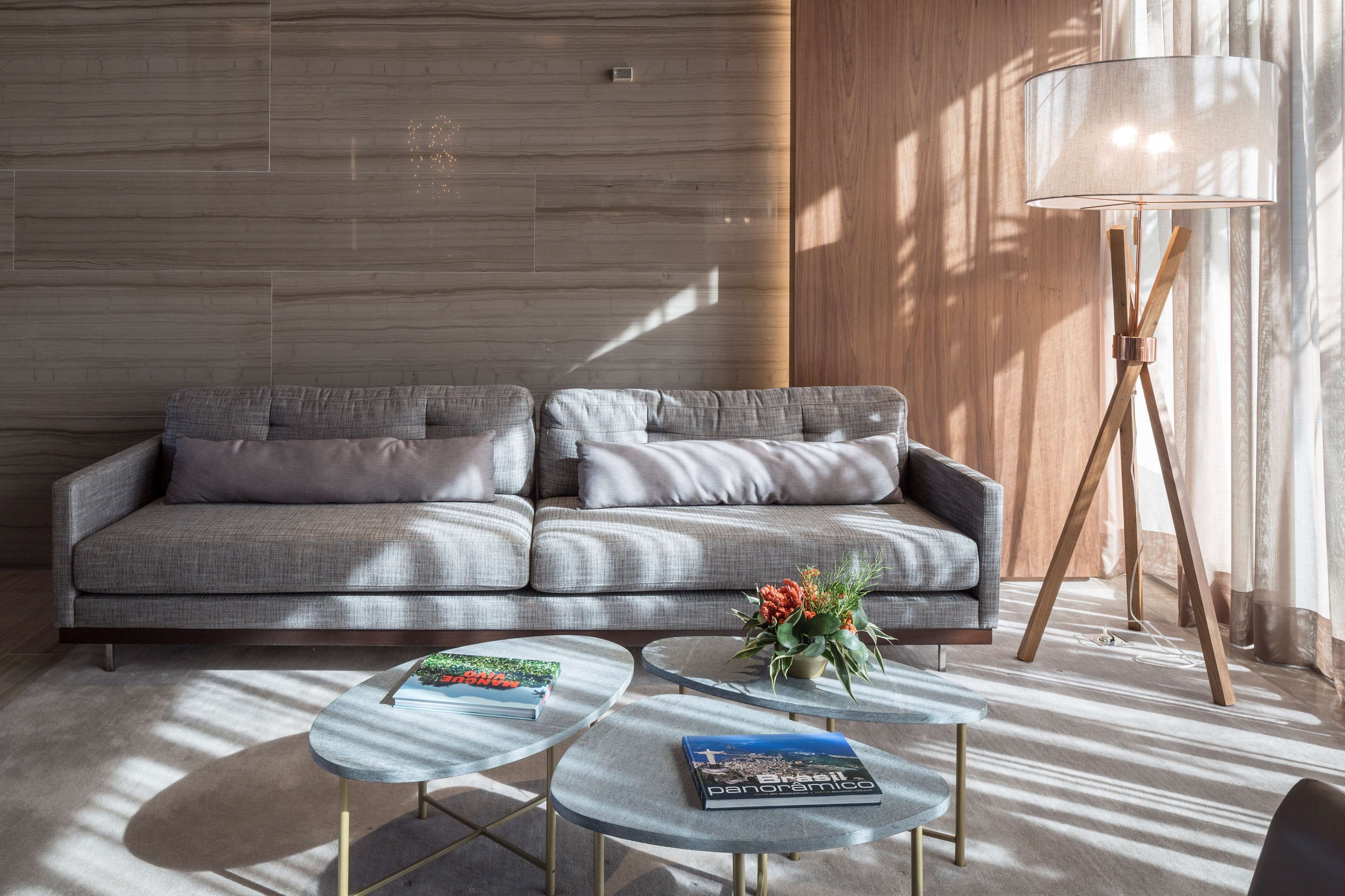 A modern living room with a grey sofa, two round coffee tables, and a floor lamp.