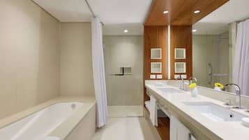 Une salle de bain moderne avec une baignoire, deux lavabos, une douche et un grand miroir.