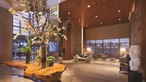 A spacious lobby with a wooden reception desk, a large vase with flowers, and a seating area with modern furniture. - Hilton Barra Rio De Janeiro (Rio de Janeiro)