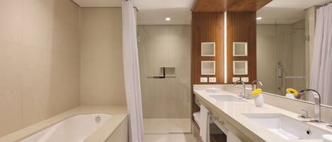 A modern bathroom with a bathtub, two sinks, a shower, and a large mirror.