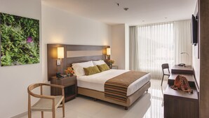 Une chambre d’hôtel moderne avec un grand lit, des lampes de chevet, un bureau et une chaise.