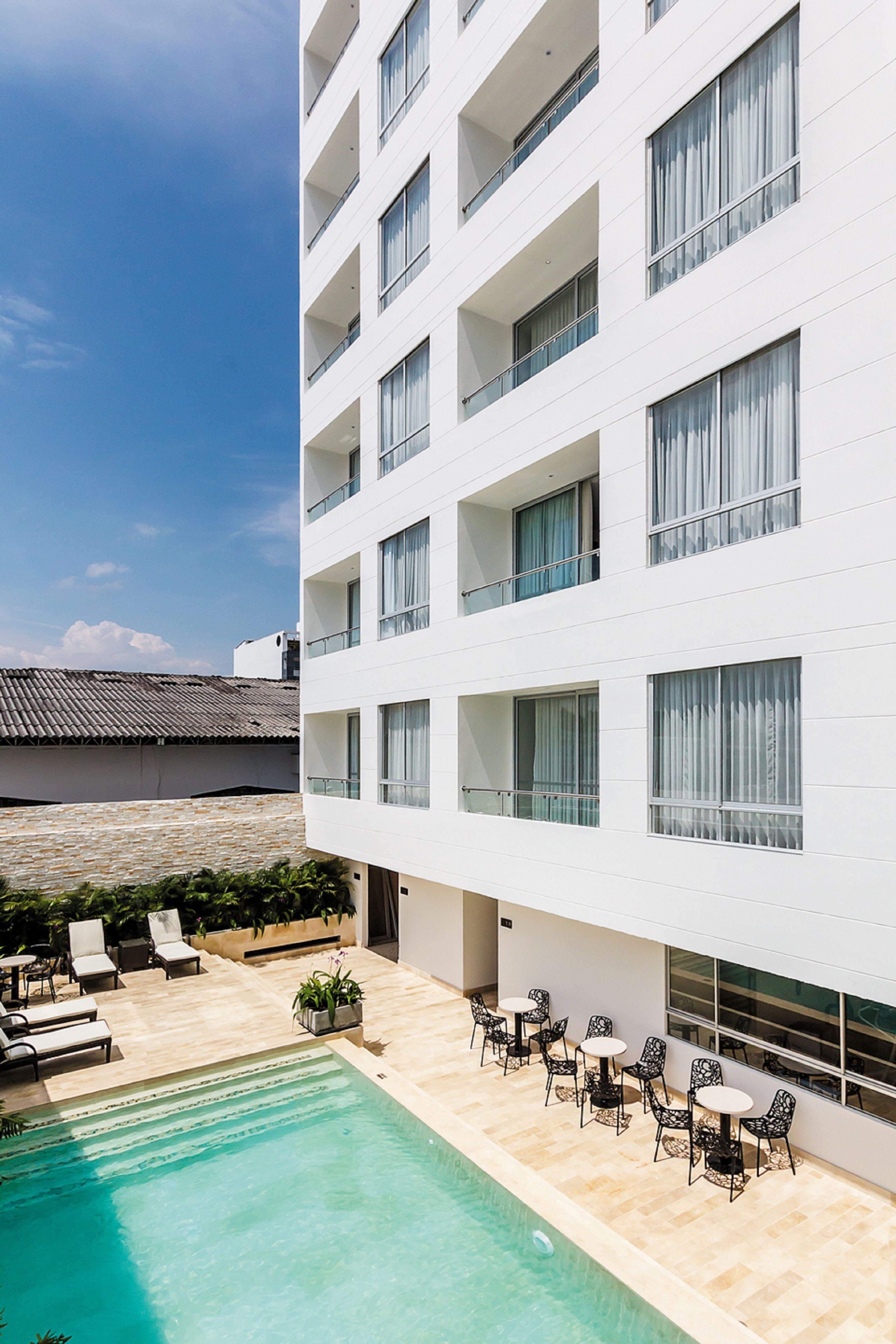 Um hotel moderno com área de piscina no terraço, espaço para sentar ao ar livre e vista para os edifícios ao redor.