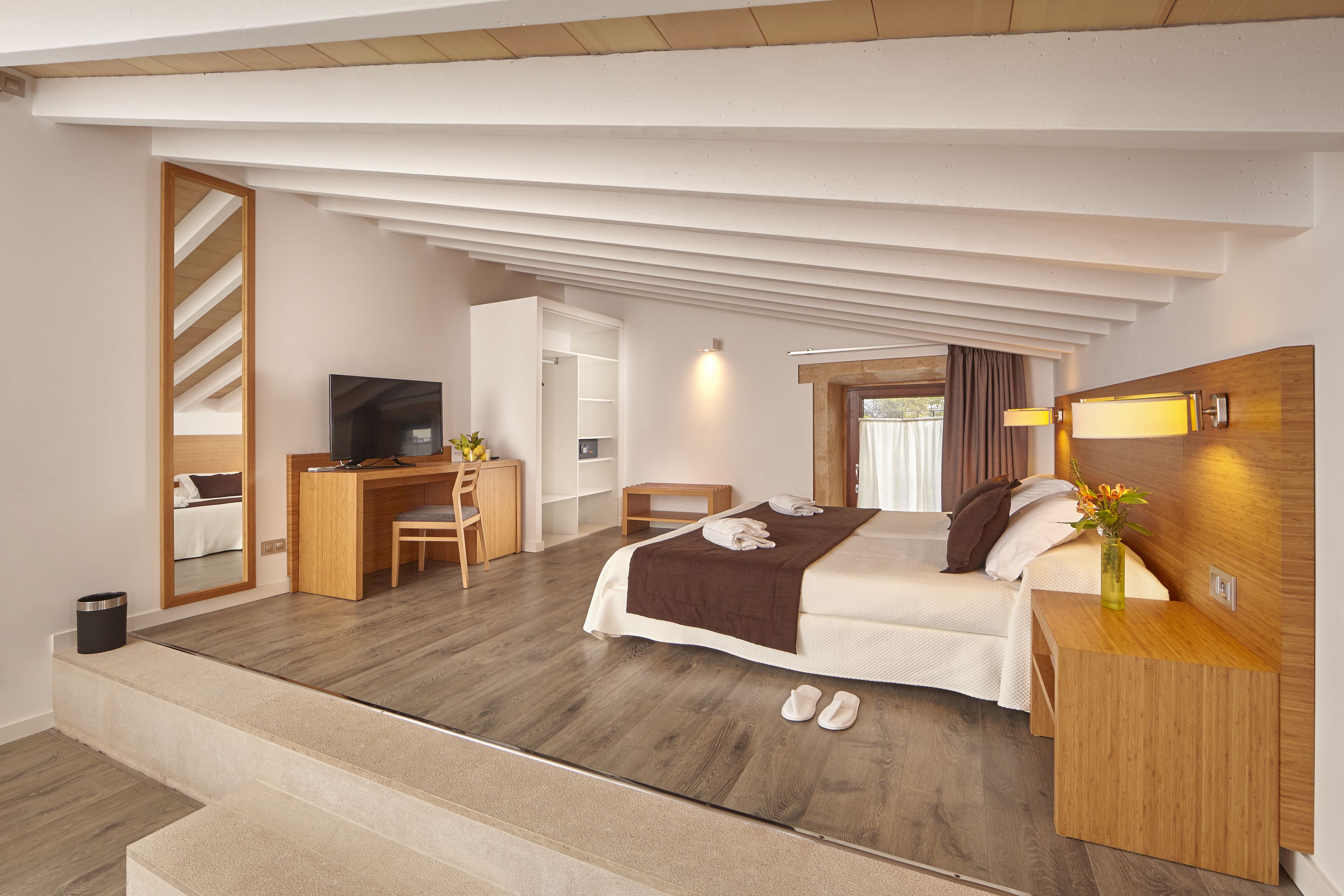 A modern hotel room with a bed, desk, and TV.