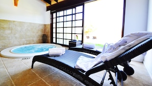 A spa room with a hot tub, a lounge chair, and a view through a large window. - Bennoc Petit Hotel (Llucmajor)