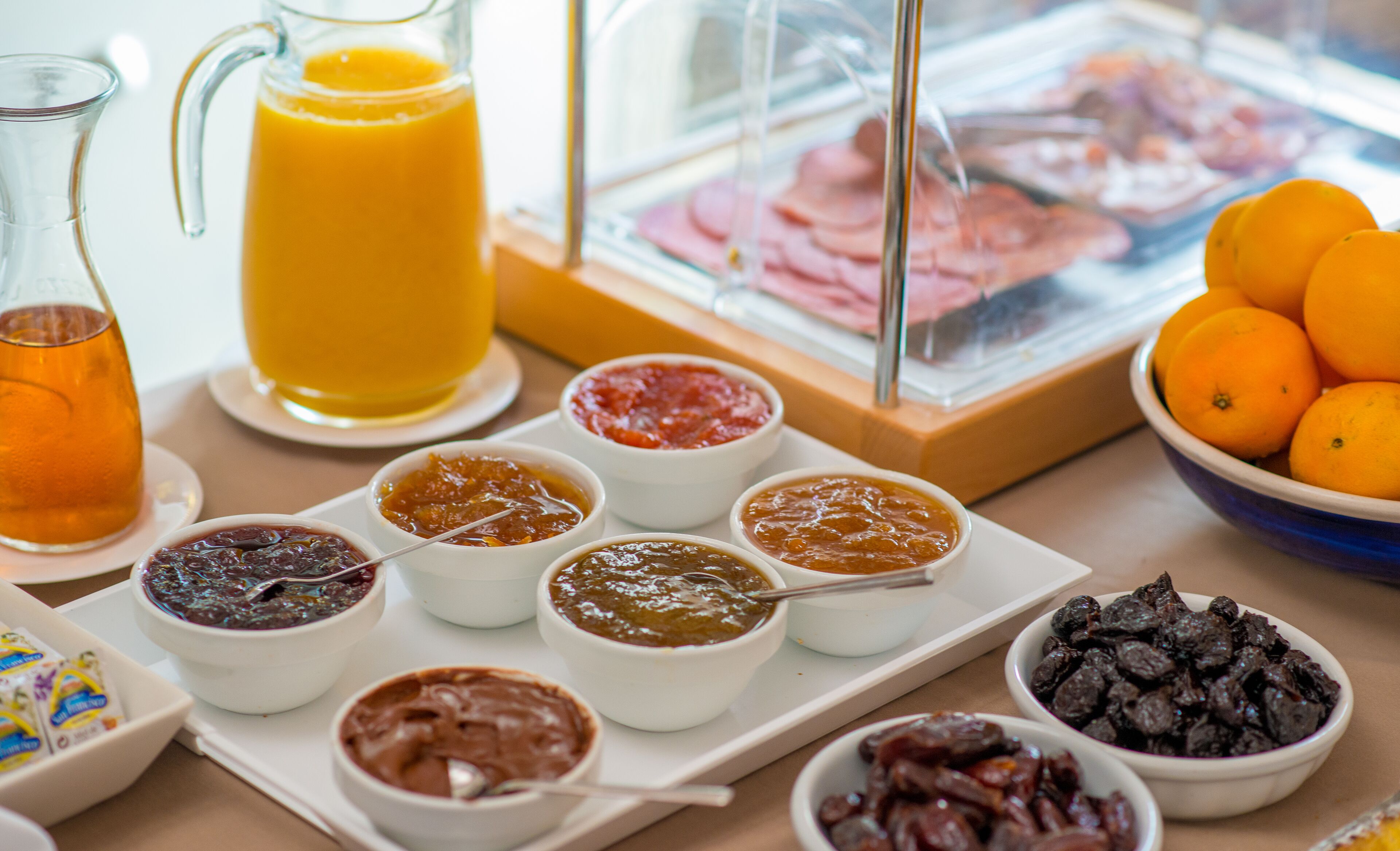 A breakfast buffet with various spreads, fruits, and beverages.
